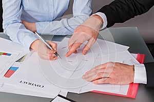 Business woman sitting at table and signing documents at office.