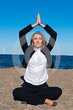Business woman sitting in yoga pose on the beach