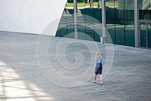 Business woman in a skirt is walking down the street, rear view