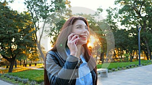 Business woman with smartphone close up in autumn park in sunset light. Girl have conversation with cell phone