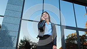Business woman with smartphone close up near office building. Girl have conversation with cell phone. Beautiful