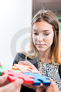 Business woman solving jigsaw puzzle with her team. Team holding