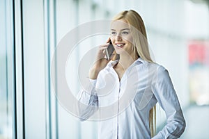 Business woman speak phone near panoramic windows. Office concept
