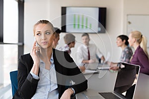 Business woman speeking on phone at office with team on meeting