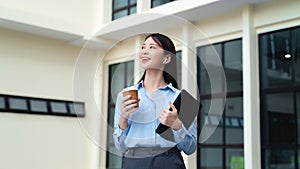 A business woman is standing in the city with a cup of coffee and a tablet