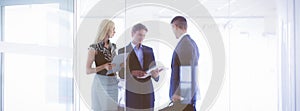 Business woman standing with her staff in background at modern office