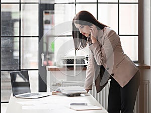 Business woman standing leaning on desk in office