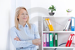 Business woman standing near the wall looking out the window thinking over the strategy.