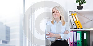 Business woman standing near the wall looking out the window thinking over the strategy.