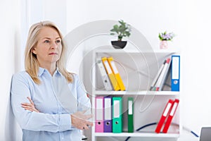 Business woman standing near the wall looking out the window thinking over the strategy.