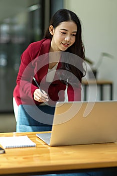Business woman standing in the office and working on her laptop computer