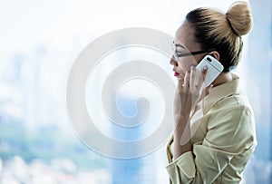 Business woman standing at skyscraper window making call