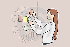 Business woman stands near scrum board with stickers and is engaged in kanban task planning