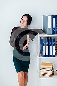 a business woman stands at a shelf with folders in the office