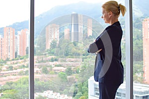 Business woman stands by the window. female joy. young happy girl in a business suit in the room smiling