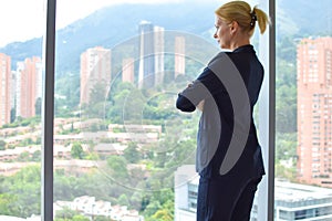 Business woman stands by the window. female joy. young happy girl in a business suit in the room smiling