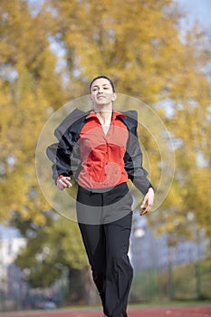 Business woman in start position ready to run and sprint on athletics racing track