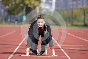 Business woman in start position ready to run and sprint on athletics racing track