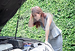 Business woman with stress look into the hood to see the car broke down