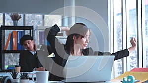 Business woman is stretching after a long working on a laptop computer in office.