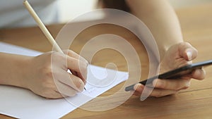 Business woman student holding phone making notes on paper, closeup