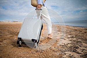 Business woman with suitcase luggage on sandy beach view on sunny day. Asian female on ocean shore having fun watching waves