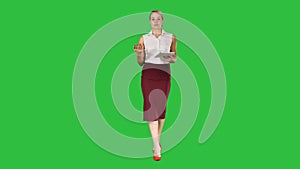Business woman with tablet walking and talking to the camera on a Green Screen, Chroma Key.
