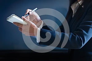 Business woman taking notes in paper on dark blue background