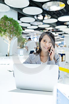 Business woman talk to mobile phone and using laptop computer