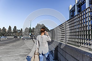 Business woman talking on her mobile phone, while walking down the street