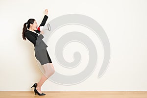 Business woman talking in megaphone with white wall