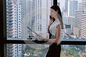 Business Woman talking with mobile phone  in Modern office building and looking documents in another hand