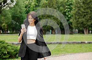 Business woman talking on a mobile phone outdoors, professional in a suit walking along an park