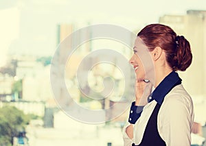 Business woman talking on mobile phone standing by office window with city urban background