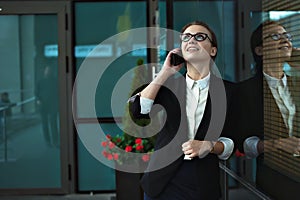 Business woman talking on smart phone on office terrace.