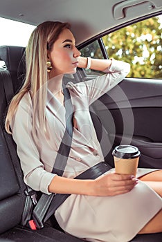 Business woman taxi car, summer city, resting after work and looking out window, holding cup coffee tea, having snack