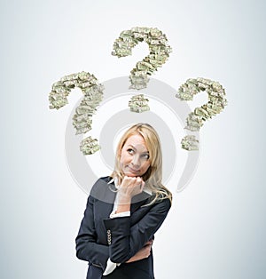 Business woman is thinking about business ideas. Three question signs are made of dollar notes.