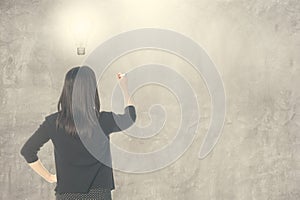 Business woman thinking idea bulb and writing on blank wall for text and background