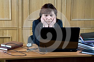 Business woman thoughtfully looks at the laptop