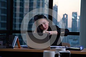 Business woman tired office worker sitting at desk using computer and doing overtime project