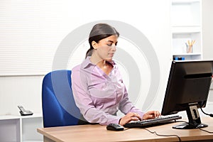 Business woman typing at computer in office