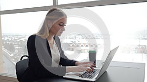 Business woman typing on laptop computer at workplace in modern office