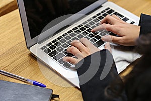 A business woman typing on a laptop at her desk