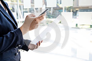 Business woman used smartphone and holding paper at the office room, Setting challenging business goals and ready to achieve the