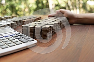 Business woman using calculator counting lots stack coins on wooden desk background texture, Money for business planning investmen