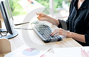 Business woman Using computer To analyze performance data from paper graph reports photo