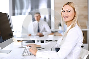 Business woman using computer at workplace in modern office. Secretary or female lawyer smiling and looks happy. Working