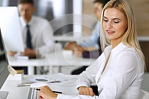 Business woman using computer at workplace in modern office. Secretary or female lawyer smiling and looks happy. Working