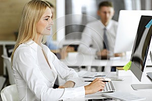 Business woman using computer at workplace in modern office. Secretary or female lawyer smiling and looks happy. Working