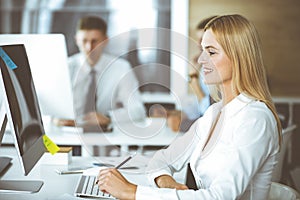 Business woman using computer at workplace in modern office. Secretary or female lawyer smiling and looks happy. Working